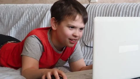 Boy using a laptop playing online games blogging, studying online Vidéo 148631203