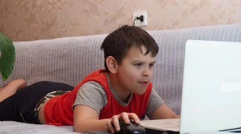 Boy using a laptop for playing online games and wearing headphone at home, a  Stock Photos
