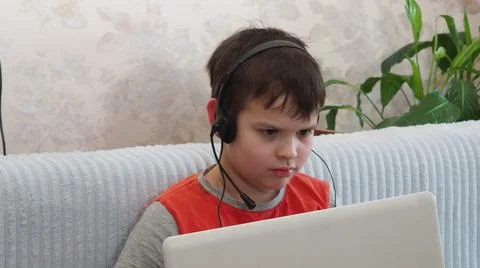 Boy using a laptop for playing online games and wearing headphone at home, a  Stock Photos