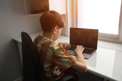 Boy using laptop for remote learning at home desk Stockfoto's