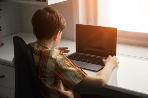 Boy using laptop for remote learning at home desk Stock Photos