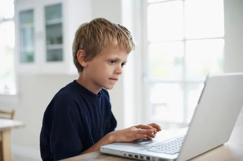 Boy Using Laptop At Table Stock Photos