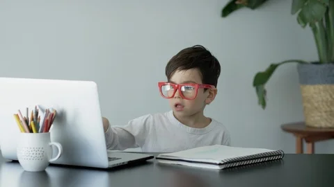 Boy using laptop while writing in book at home Stock Footage 106316705