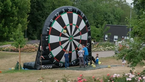 Boy using a long pole to reach a soccer ball on a giant inflatable dartboard Stockbeeldmateriaal 337404242