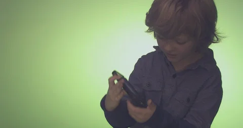 Boy using mobile phone against green background Stock Footage 99989998