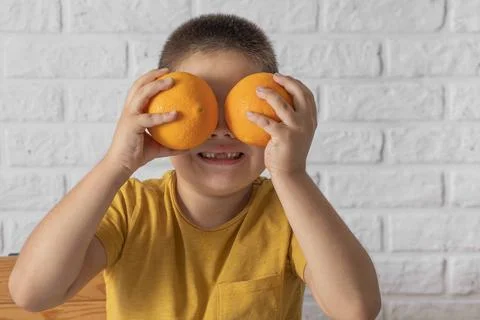 Boy using oranges as playful goggles, bringing attention to the significance of Stock Photos