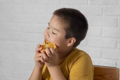 Boy using oranges as playful goggles, bringing attention to the significance of Stock Photos