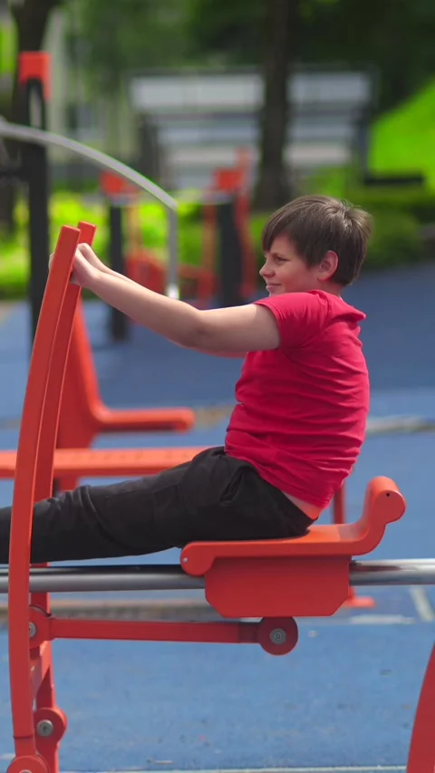 Boy Using Outdoor Rowing Machine at Public Fitness Park, Healthy Stock Footage 337880006