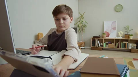 Boy Using Smartphone and Computer when Doing Homework at Table Stock Footage 334024635
