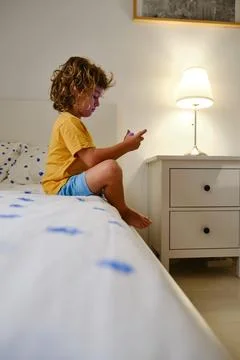 Boy using smartphone on bed Stock Photos