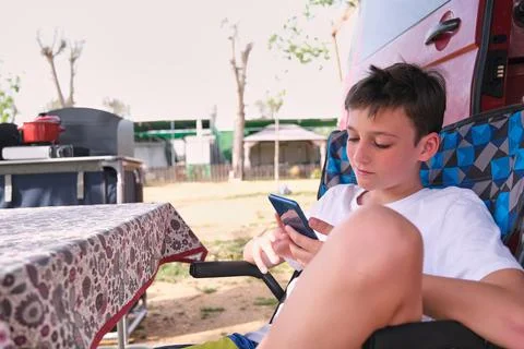 Boy using smartphone outside caravan Stock Photos