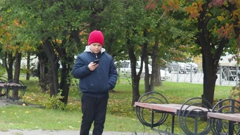 Boy using smartphone in park.  school  boy in casual wear talking on the phone 库存影片 164472269