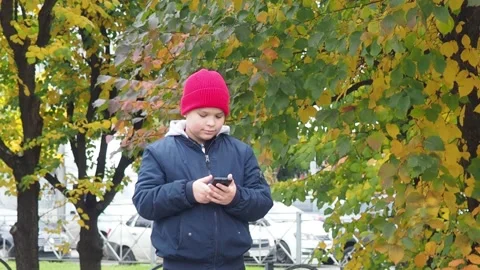 Boy using smartphone in park.  school  boy in casual wear talking on the phone 库存影片 164472300