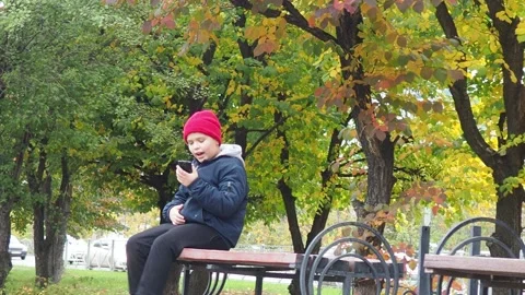 Boy using smartphone in park.  school  boy in casual wear talking on the phone 库存影片 164472324