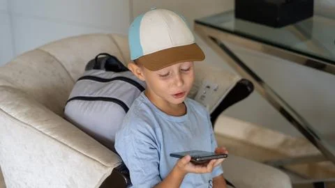 Boy using smartphone while sitting on a sofa in a hotel room Photos