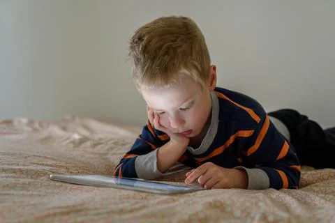 Boy using tablet on bed Stock Photos