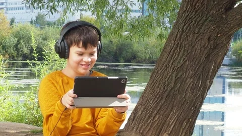 Boy using tablet computer, teenager relaxing in the park Video stock 270936866