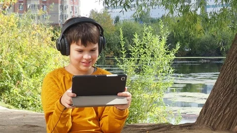 Boy using tablet computer, teenager relaxing in the park Video stock 270936899