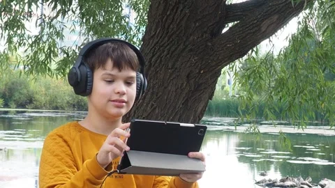 Boy using tablet computer, teenager relaxing in the park Video stock 270936906