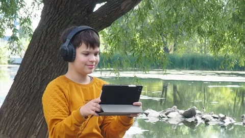 Boy using tablet computer, teenager relaxing in the park Video stock 270936940