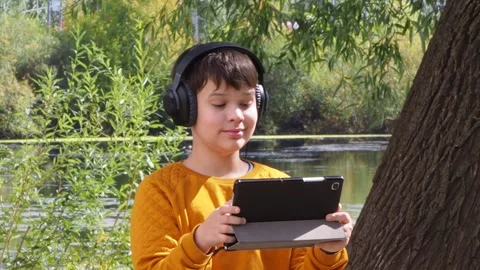 Boy using tablet computer, teenager relaxing in the park Video stock 270936966