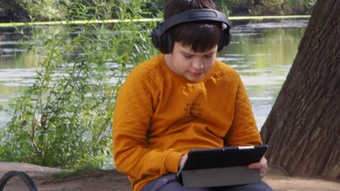 Boy using tablet computer, teenager relaxing in the park Video stock 270936969