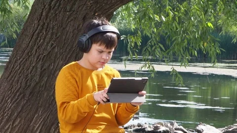 Boy using tablet computer, teenager relaxing in the park Video stock 270937003