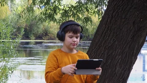 Boy using tablet computer, teenager relaxing in the park Video stock 270937004