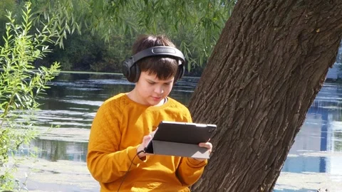 Boy using tablet computer, teenager relaxing in the park Video stock 270937014