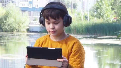 Boy using tablet computer, teenager relaxing in the park Stock Footage 270937043