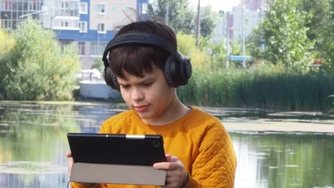 Boy using tablet computer, teenager relaxing in the park Video stock 270937052