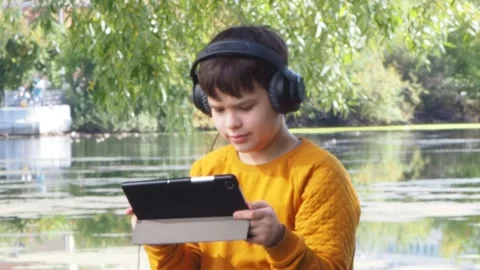 Boy using tablet computer, teenager relaxing in the park Video stock 270937069
