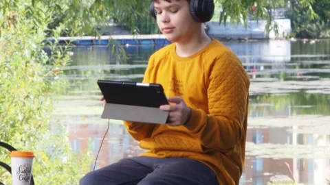 Boy using tablet computer, teenager relaxing in the park Video stock 270937097