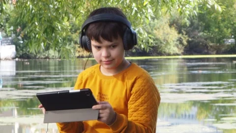 Boy using tablet computer, teenager relaxing in the park Stock Footage 270937100
