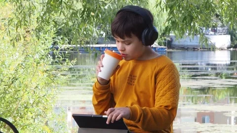 Boy using tablet computer, teenager relaxing in the park Stock Footage 270937176