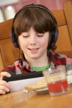 Boy Using Tablet Computer Whilst Eating Breakfast Stockfoto's