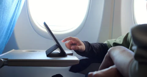 Boy using tablet during flight, close view of mobile device and hand Stock Footage 303993848