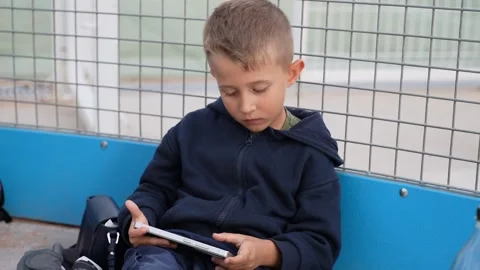 Boy Using Tablet While Sitting on Bench Outdoors 스톡 동영상 333530168