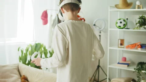Boy using virtual reality glasses with controllers, playing video games, child Stock Footage 202324005