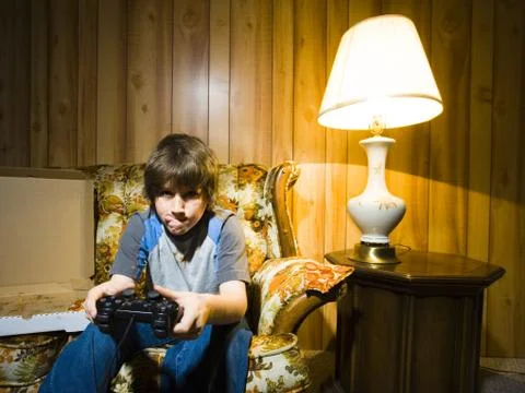 Boy with video game controller on sofa Stock Photos