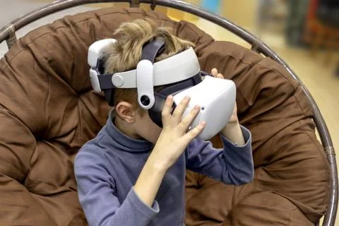 Boy in virtual reality headset in comfy chair playing Stock Photos