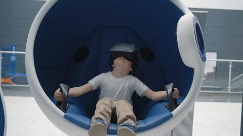 Boy in a virtual reality headset in a moving interactive chair Stock Footage 106750465