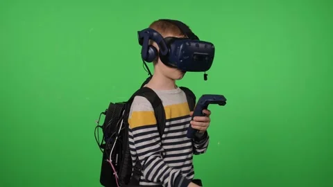 A boy in a virtual reality headset is playing a sword game on a green background Stock Footage 317000987