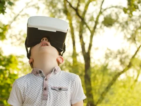 Boy in a virtual reality helmet on a background of green forest. Stock-Fotos