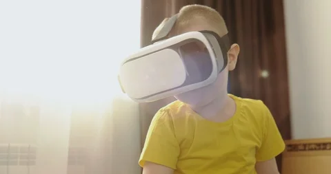 Boy in virtual reality helmet sits in game room, plays VR, plunges into virtual Stock Footage 123355206
