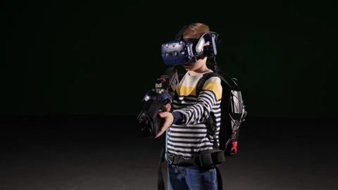 A boy in a VR headset uses virtual reality glasses and a machine gun. Stock Footage 316591837