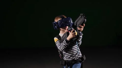 A boy in a VR headset uses virtual reality glasses and a machine gun. Stock Footage 317299816