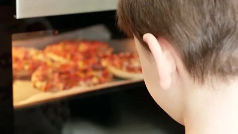 A boy is waiting for the pizza to be cooked, Oven-baked pizza and the hungry  Stock Footage 166749726