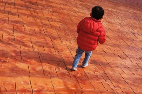 A Boy Walk Through Shadows Cast on a Vibrant Tiled Surface Foto stock