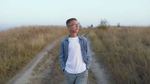 A boy walking alone in the hills at sunset Stockbeeldmateriaal 140181806